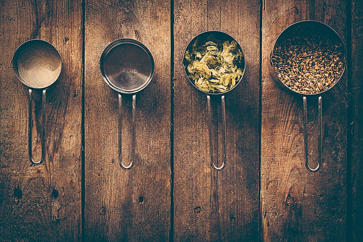 Different ingredients for making beer in measuring cups representing trends in the craft beer industry