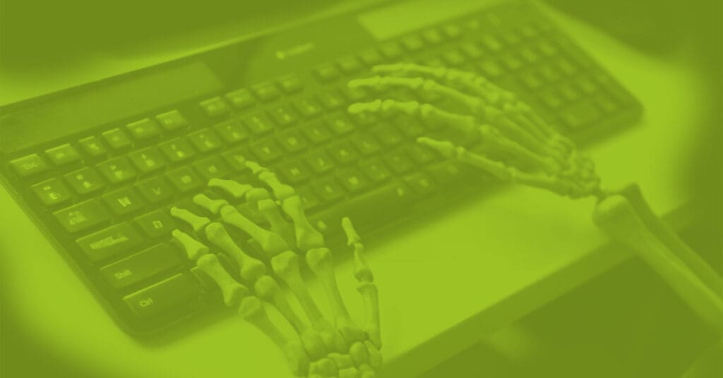 Photo of skeleton hands resting on computer keyboard. Understanding open source vs proprietary CMS is important when deciding to retire your old content management system.