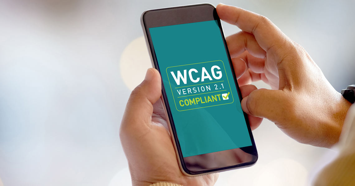 Hands holding a mobile phone that shows WCAG Version 2.1 Compliant