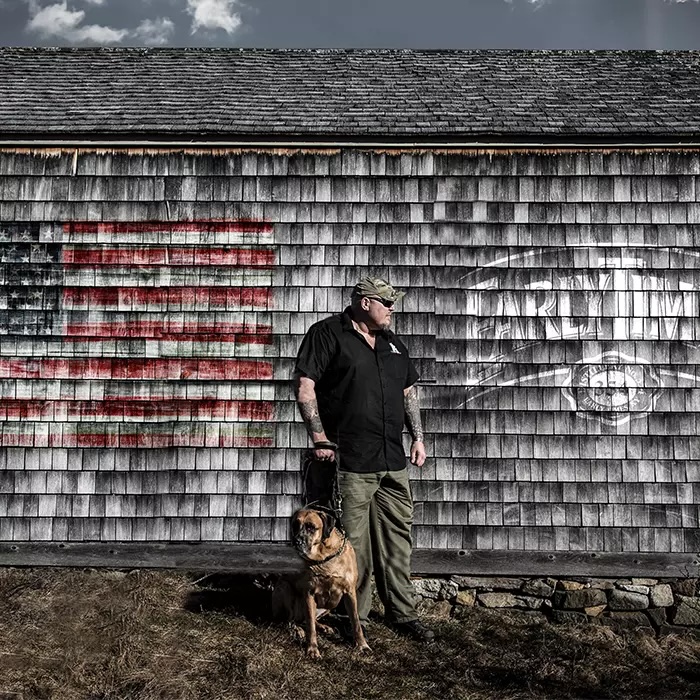 Early Times Case Study - an image of a man and his service dog standing outside of a building painted with the Early Times logo and American flag