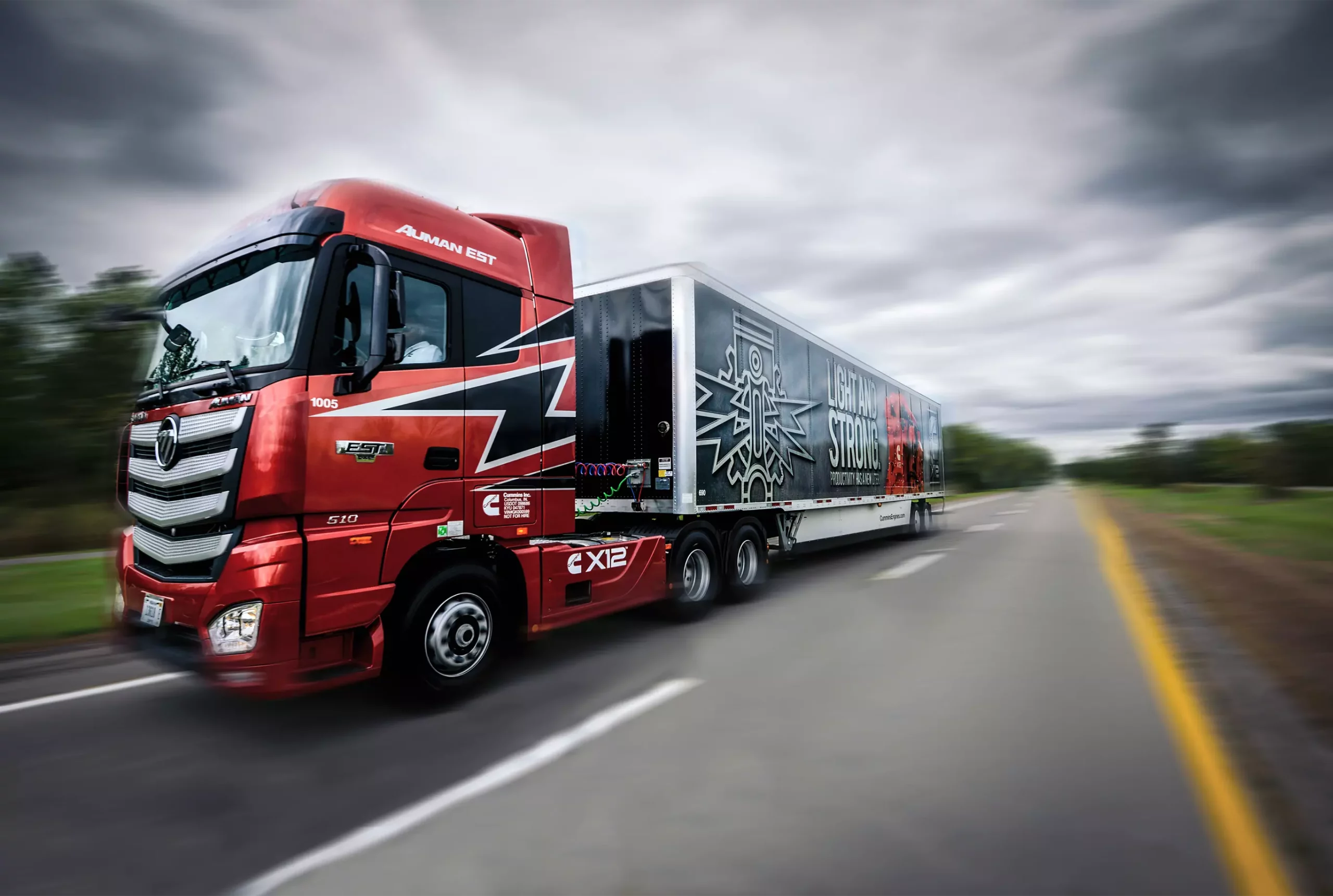 large semi-trauker truck with cummins branding driving on a two lane road