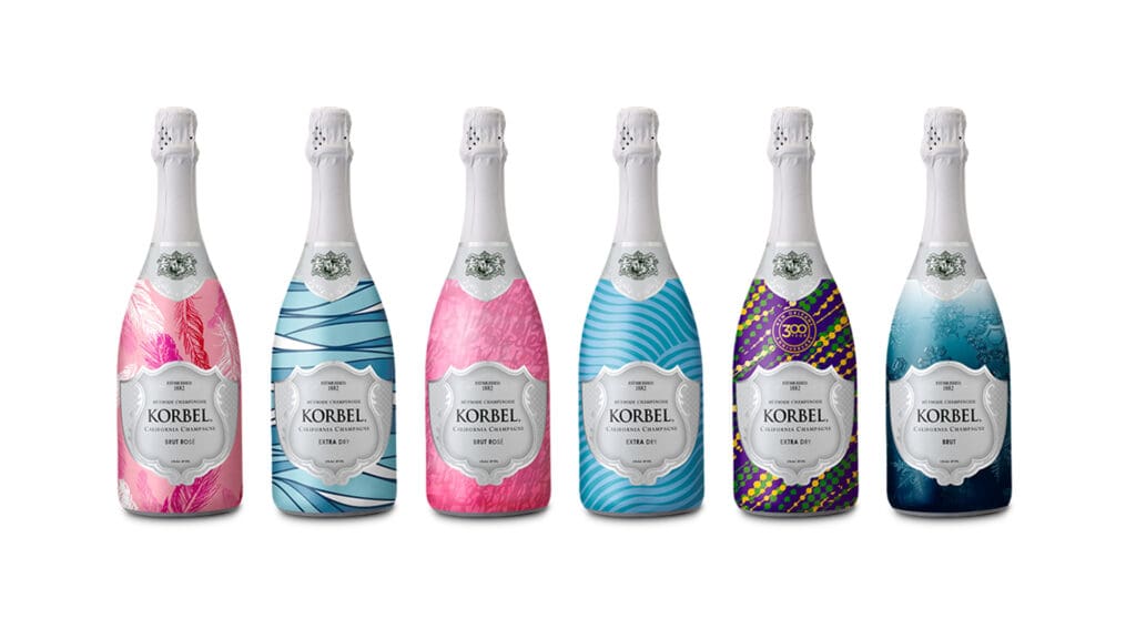 Korbel Champagne - Brut Rose and Extra Dry bottles with pink, blue and purple labels and patterns of feathers, stripes, and snowflakes