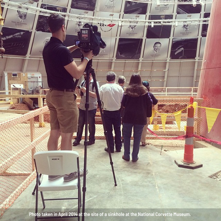 Crowd and man with news camera standing around sinkhole in National Corvette Museum, one of several examples of successful crisis communication planning.