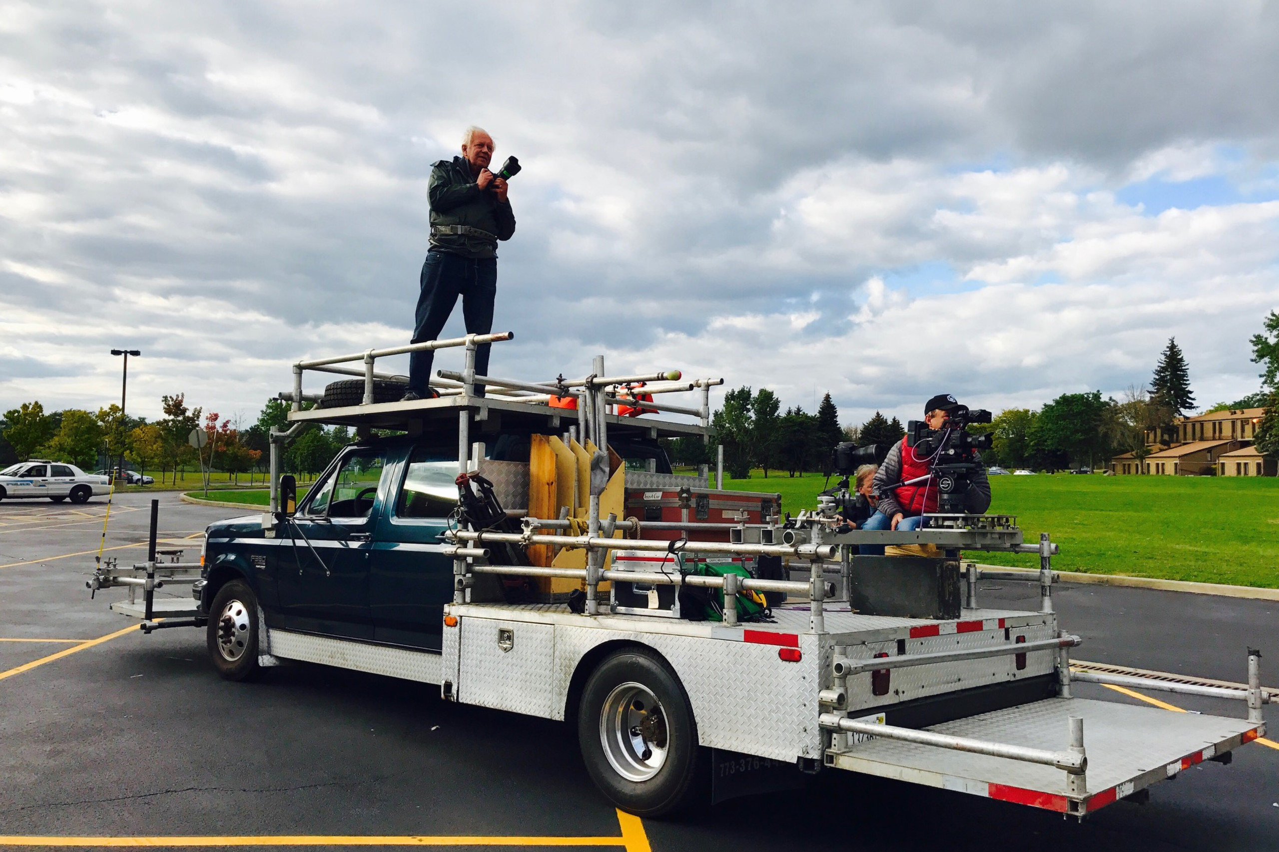 Man standing on top of video truck mounted with camera