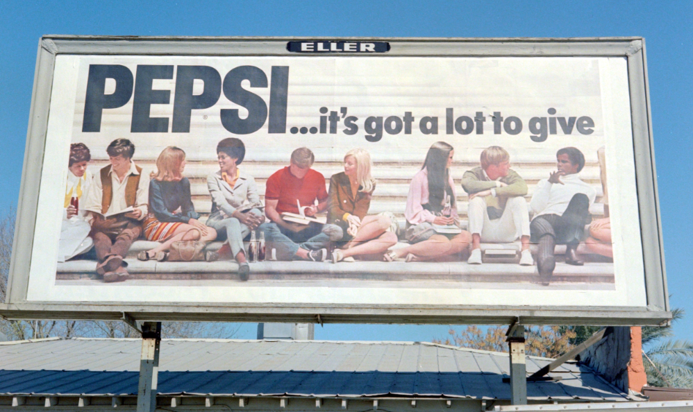 Billboard from the 1980s featuring people of different races sitting on steps with books