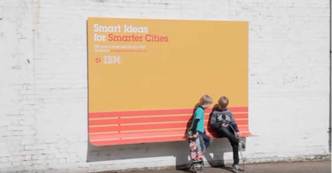 Two children sitting in front of a billboard advertisement for IBM with an effective marketing message