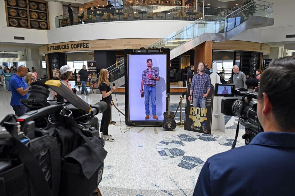 Media cameras capture the life-sized Dierks Bentley hologram activation at Louisville Muhammad Ali International Airport