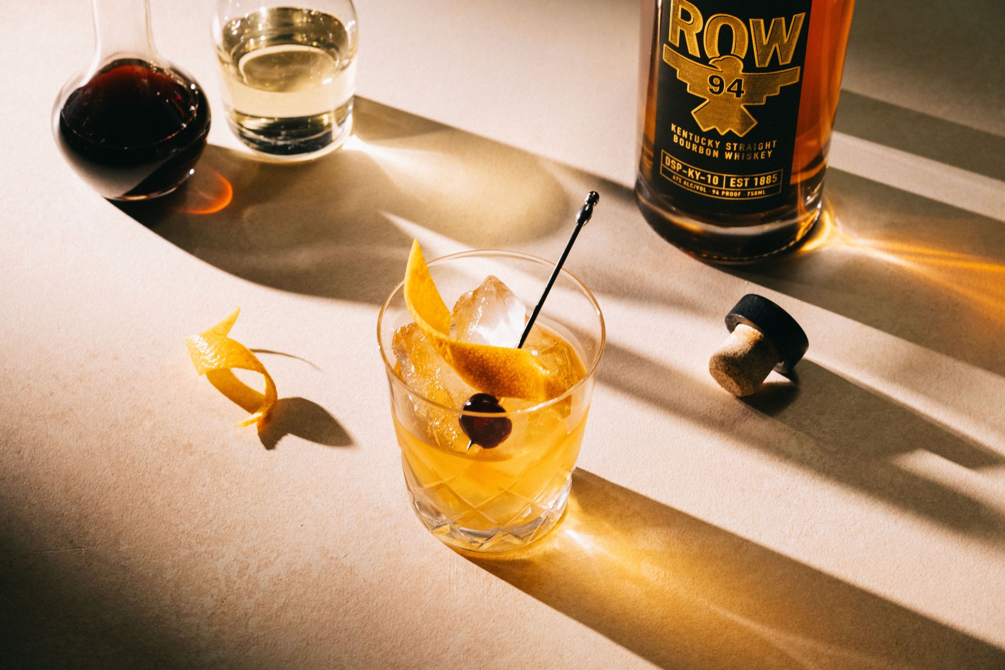 ROW 94 whiskey bottle and Old Fashioned cocktail in warm light