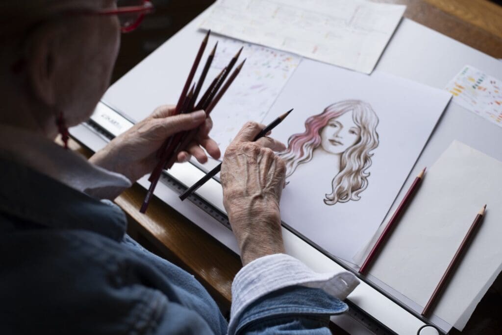 Close-up of Claudia Hammer’s hands sketching the goddess illustration with colored pencils