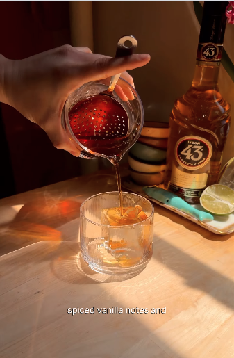 Creator Reel frame of a cocktail being strained over ice beside a bottle of Licor 43