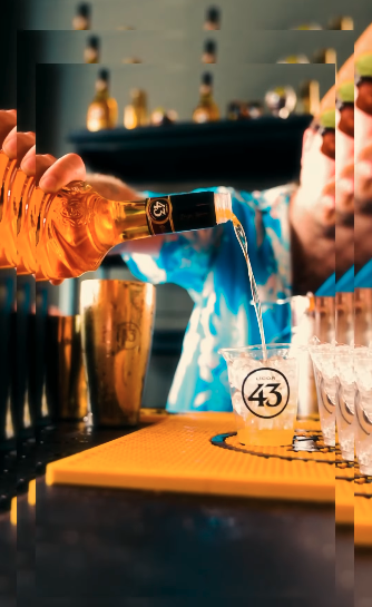 Creator video frame of a bartender pouring Licor 43 into cups on a bar mat